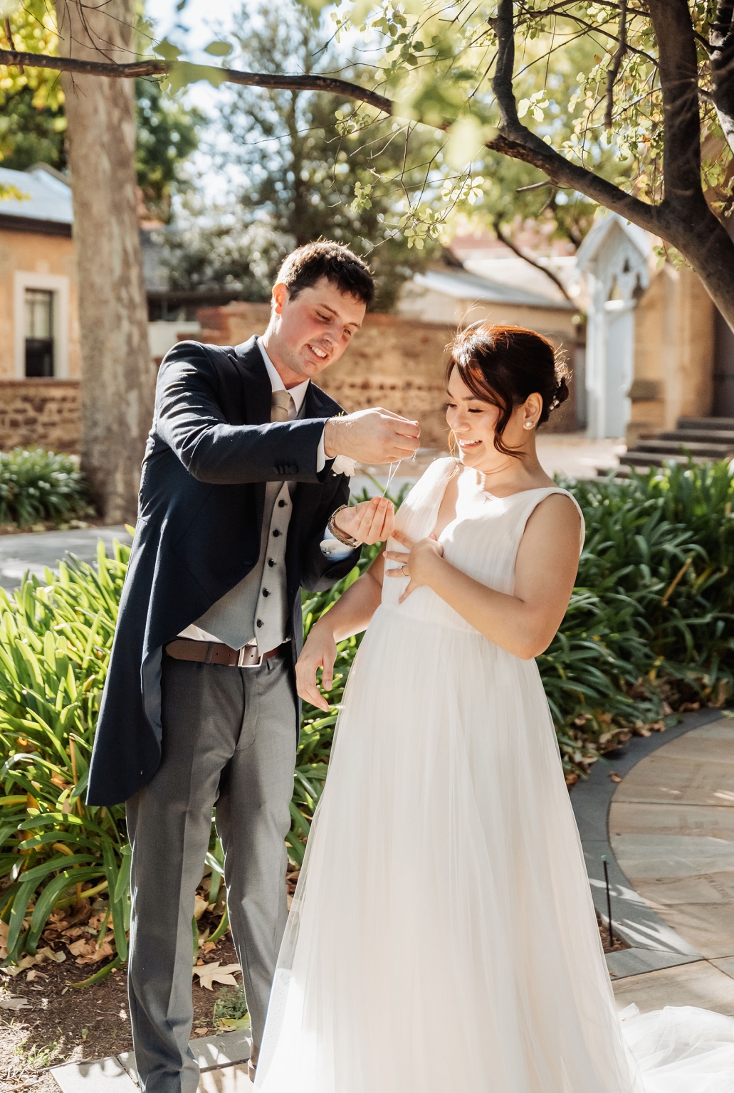 adelaide's st peter's cathedral wedding - irish & nick 9 Bride and groom share a joyful moment in a sunlit garden wedding venue.