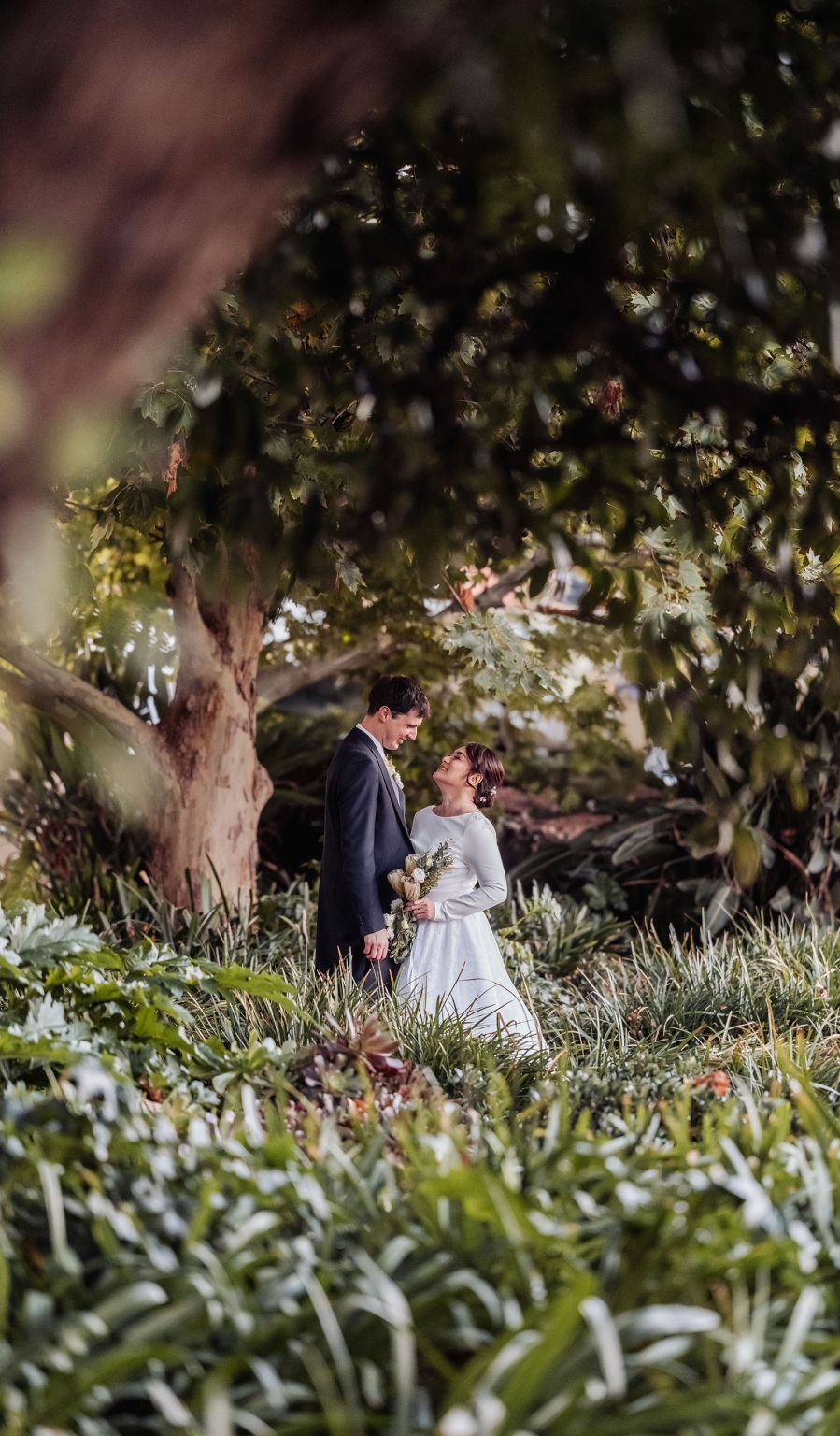 adelaide's st peter's cathedral wedding - irish & nick 46 Romantic garden wedding couple portrait beneath lush greenery.