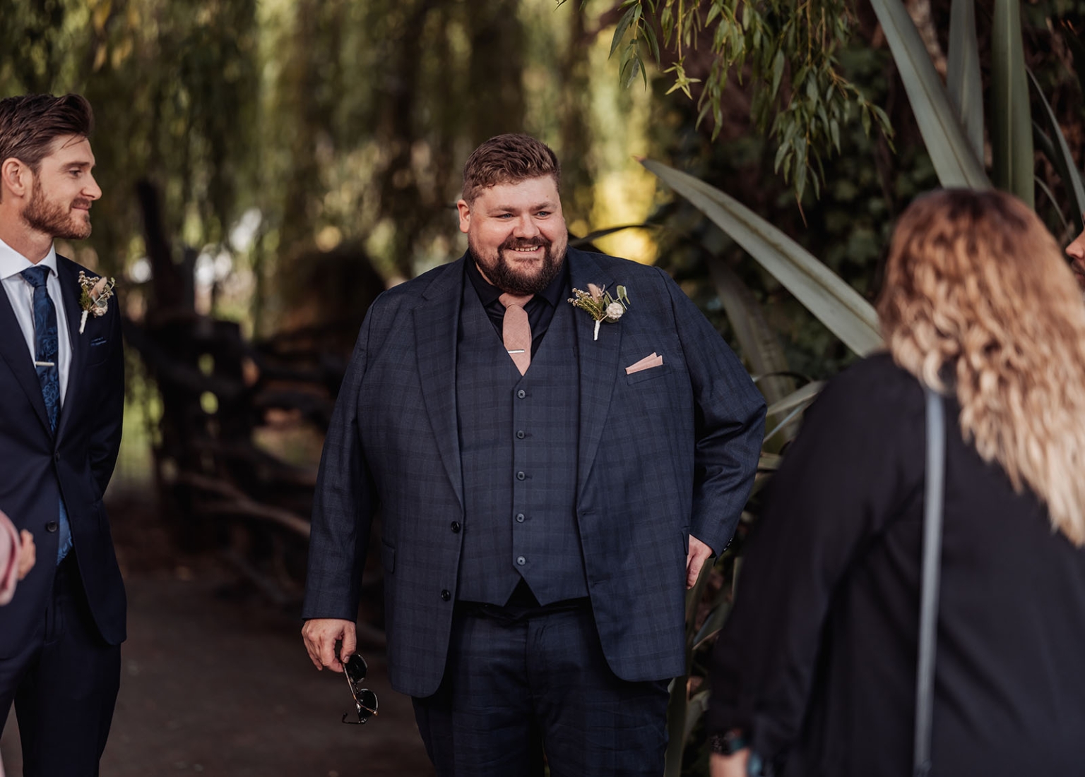 comida wedding - georgia & james 7 Elegant garden wedding conversation amidst greenery, featuring stylish men in suits.