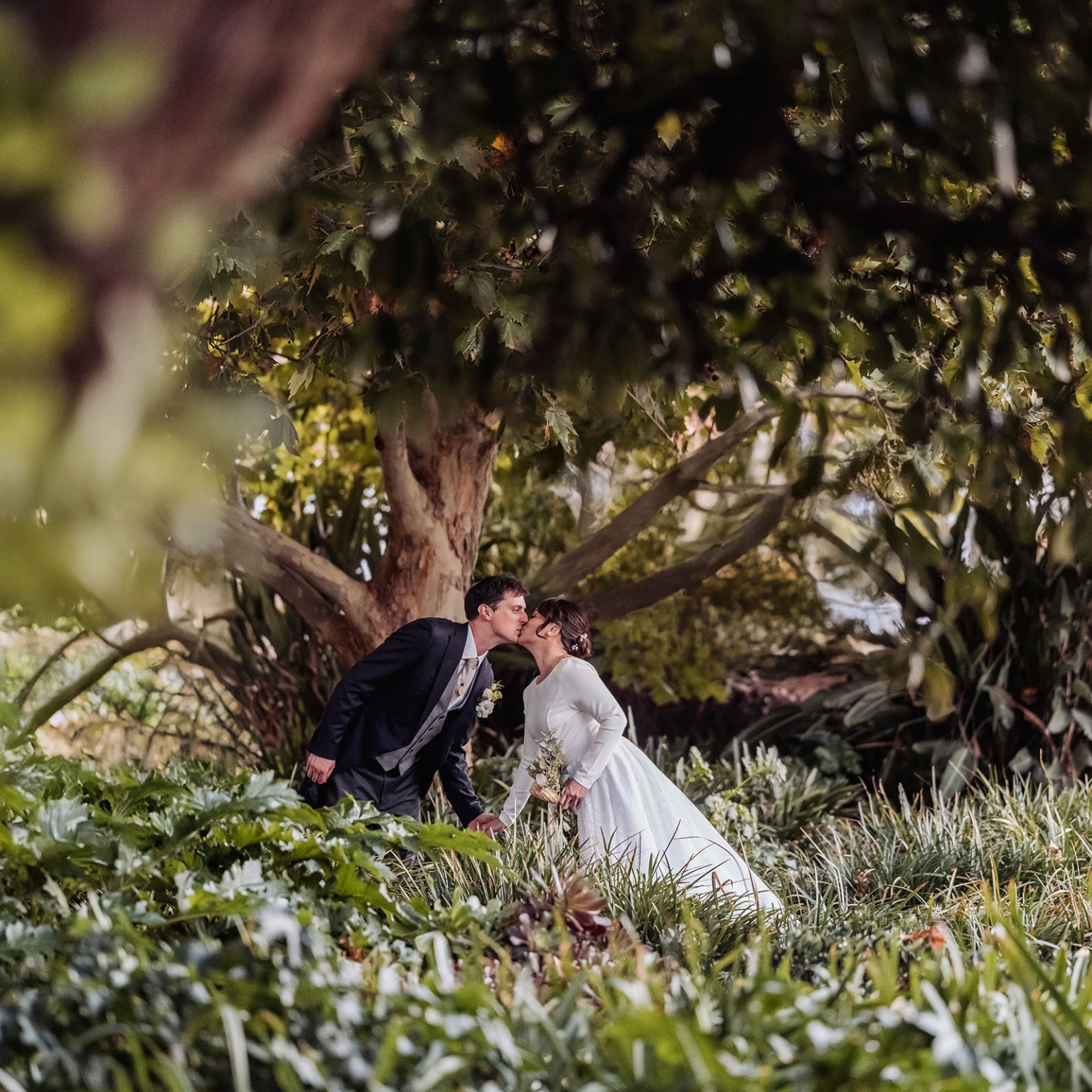 adelaide's st peter's cathedral wedding - irish & nick 48 Bride and groom kissing in lush garden wedding portrait.
