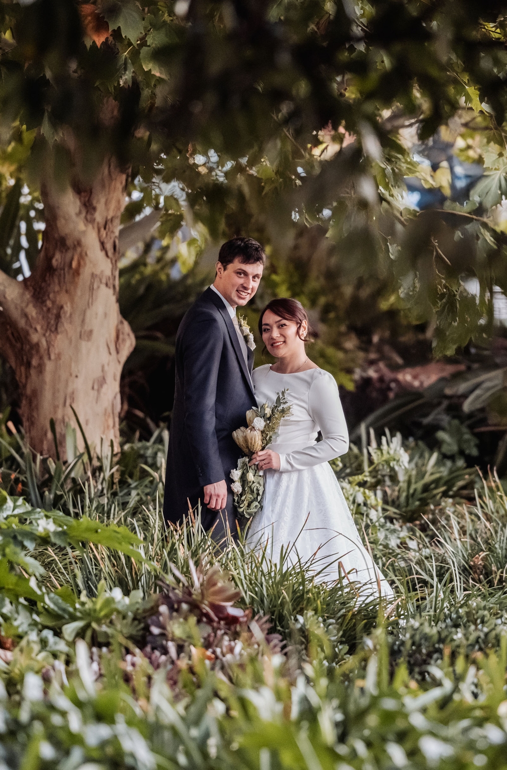 adelaide's st peter's cathedral wedding - irish & nick 47 Bride and groom garden wedding portrait surrounded by lush greenery.