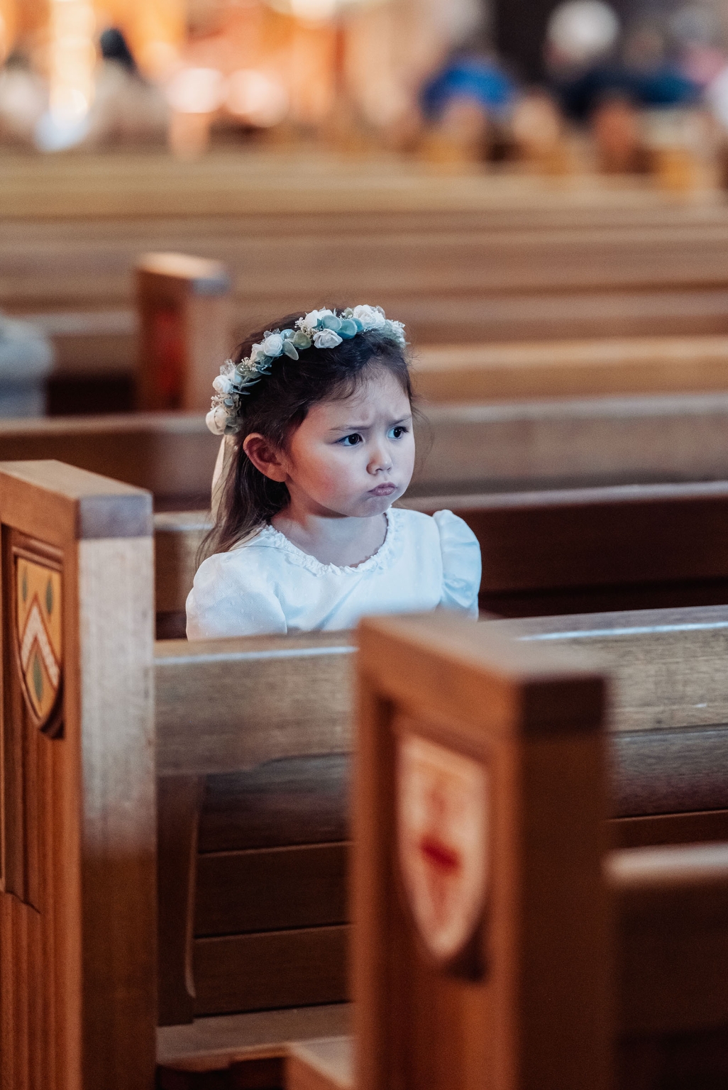 adelaide's st peter's cathedral wedding - irish & nick 11 Young flower girl in white dress sitting in wooden church pew.