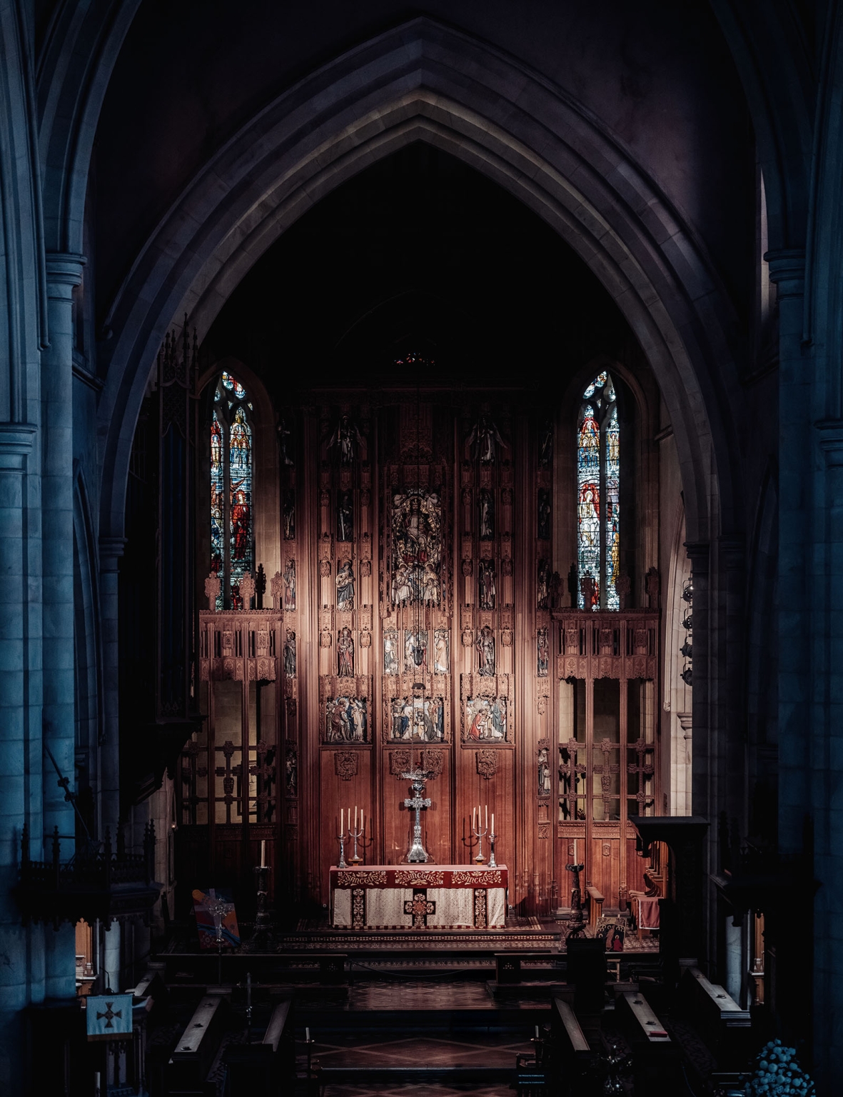 adelaide's st peter's cathedral wedding - irish & nick 2 Gothic cathedral altar with carved wooden reredos, stained glass windows, and pews.
