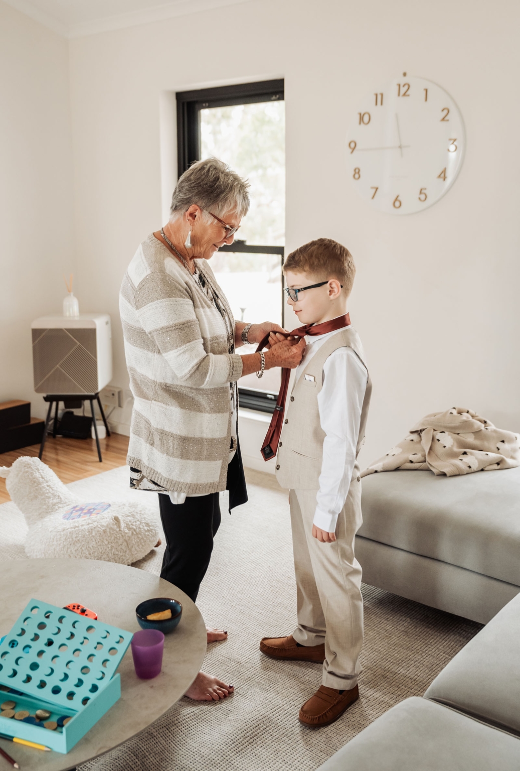 the lane vineyard wedding - caitlyn & craig 62 Grandmother helps boy with tie in cozy, warm living room setting.