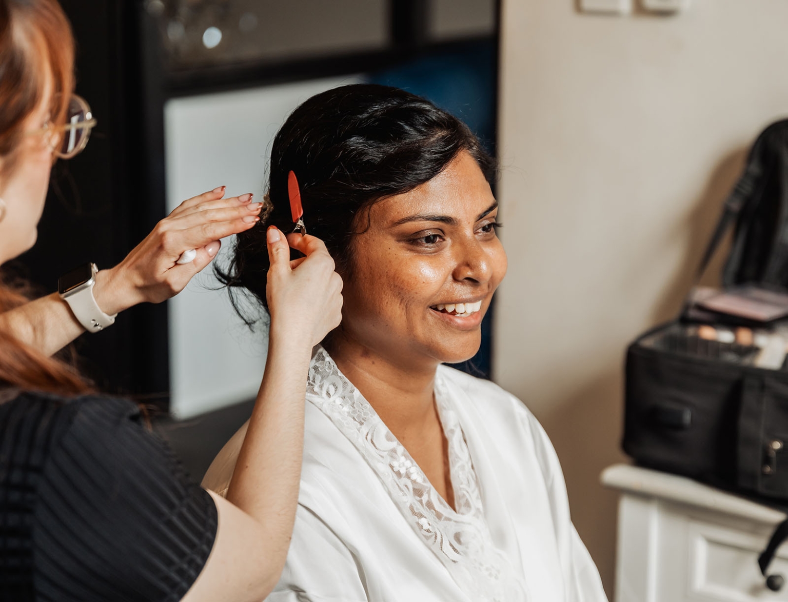 the night before the wedding: how brides can wake up with camera-ready hair 109 Woman smiling during a hairstyling session, displaying elegance and beauty preparation.