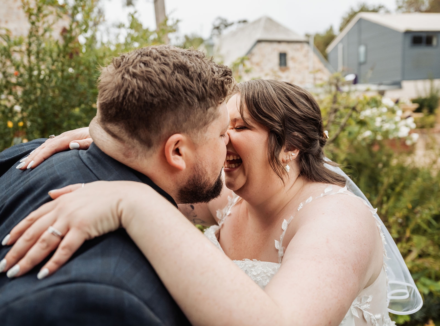 comida wedding - georgia & james 30 Bride and groom embracing joyfully in garden wedding setting.