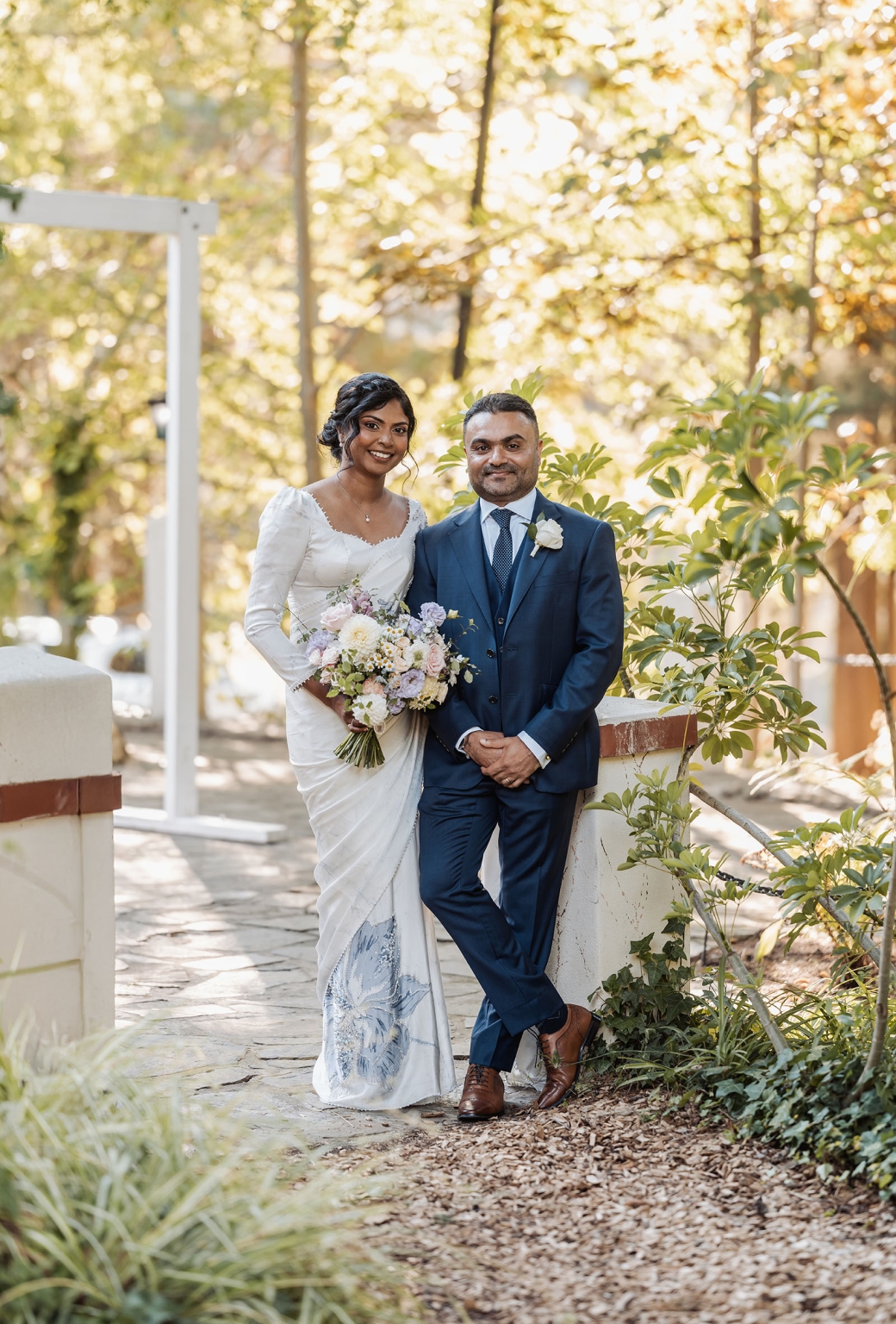 manor wedding in basket range - methmini & aravinda 146 Elegant couple celebrating wedding in nature with vibrant foliage and sunlight.