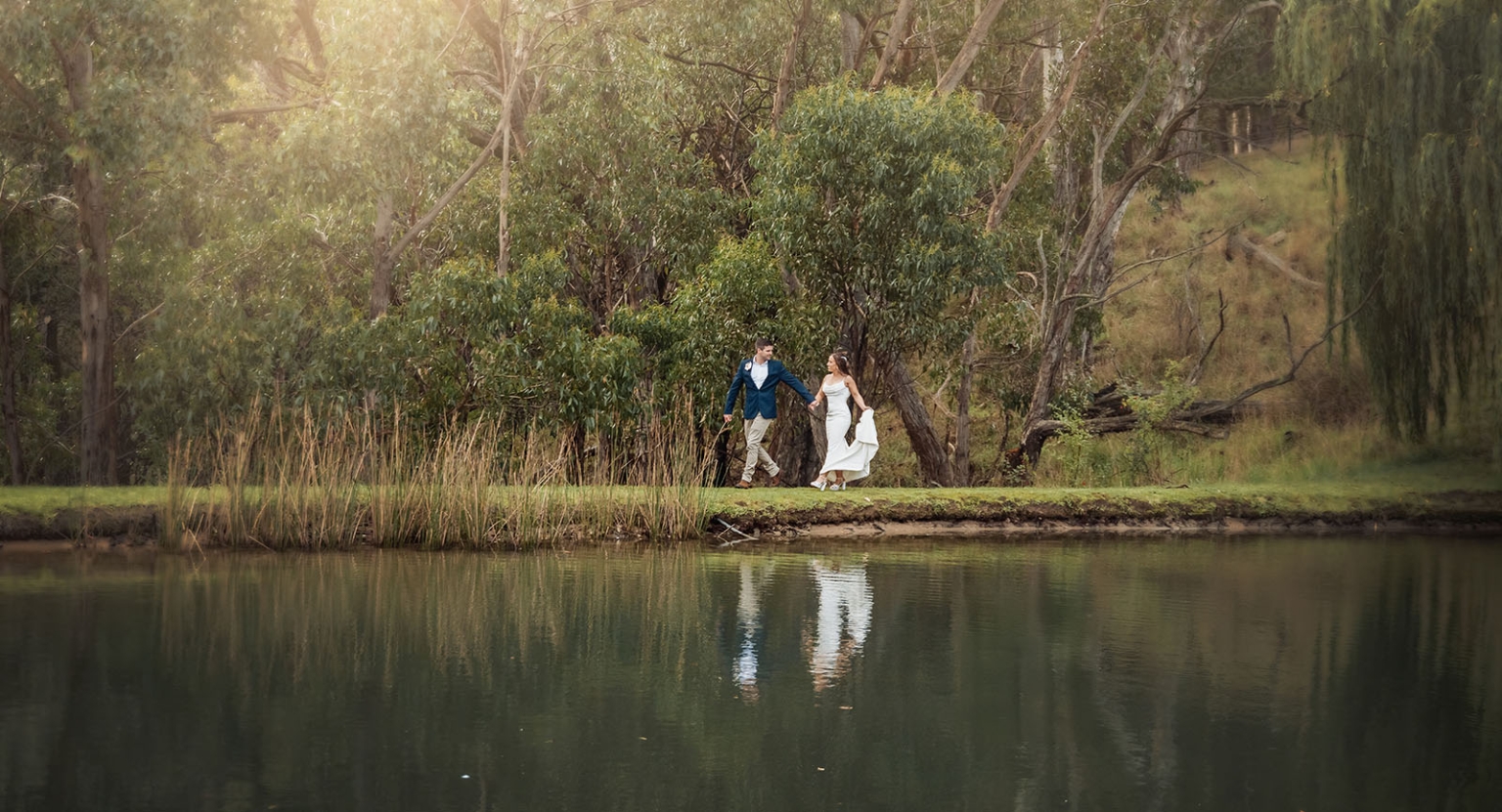 the lane vineyard wedding - caitlyn & craig 106 Romantic couple walking by serene lake, reflection of trees and formal attire.