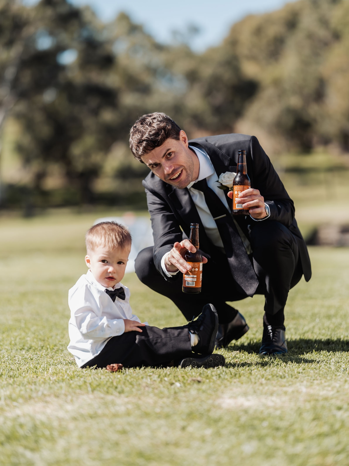 lloyd brothers wedding - dajana & tom 22 Man and toddler in formal attire enjoying a playful moment at an outdoor wedding.