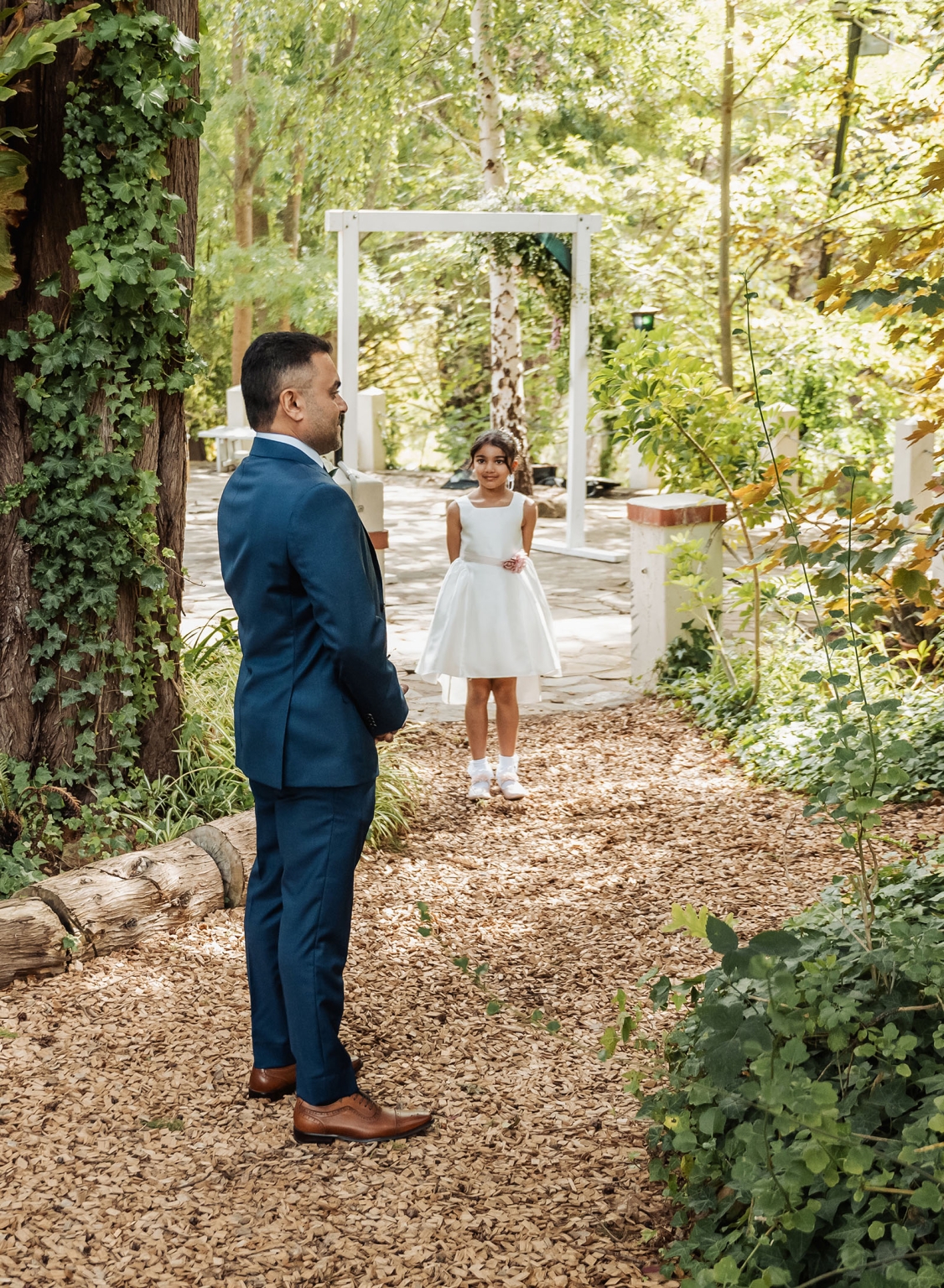 manor wedding in basket range - methmini & aravinda 123 Wedding scene: man in navy suit and girl in white dress in garden setting.
