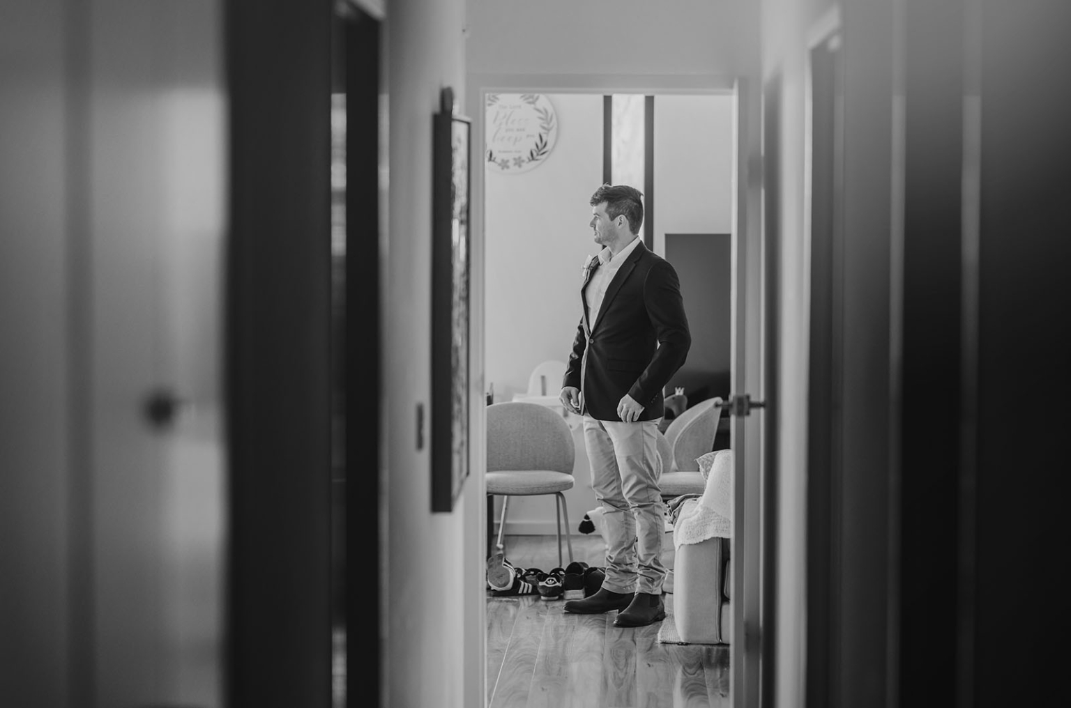 the lane vineyard wedding - caitlyn & craig 72 Man in a suit stands in a hallway, framed by doors, hinting at a family setting.