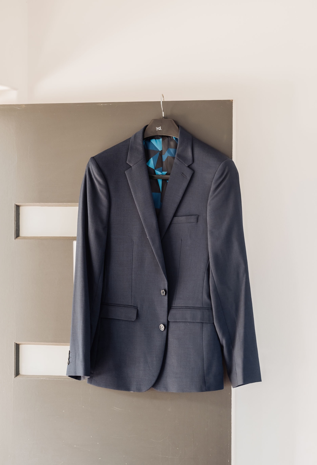 the lane vineyard wedding - caitlyn & craig 63 Navy blue suit jacket on wooden door with geometric lining, showcasing elegance and sophistication.