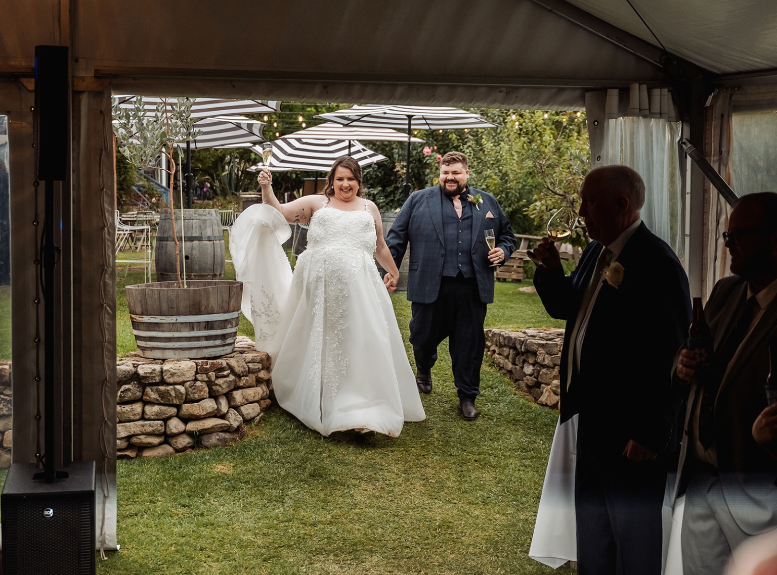 comida wedding - georgia & james 45 Bride and groom jubilant entrance at garden wedding reception with champagne.