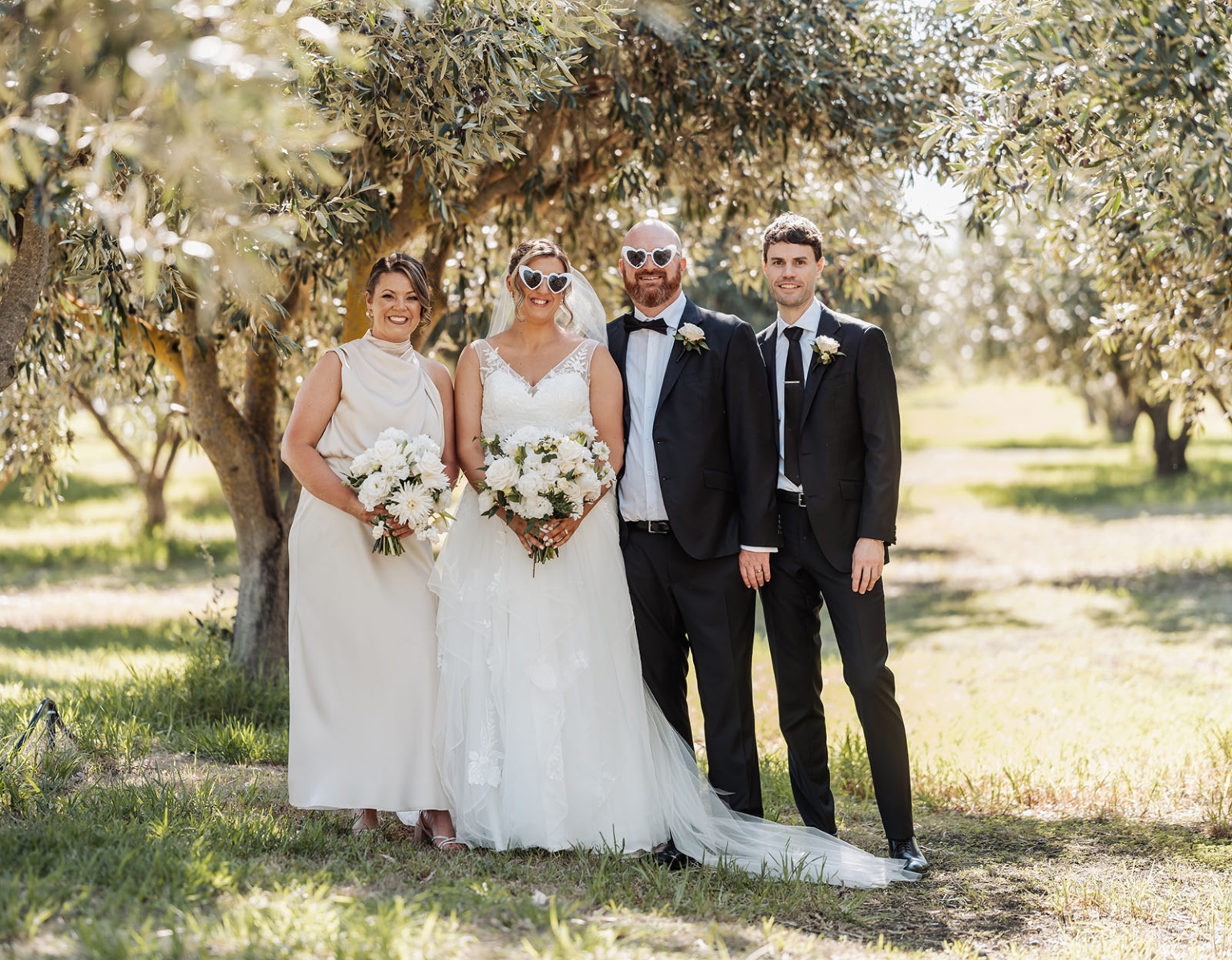 lloyd brothers wedding - dajana & tom 35 Outdoor wedding scene with bride, groom, bridesmaid, groomsman under olive trees.