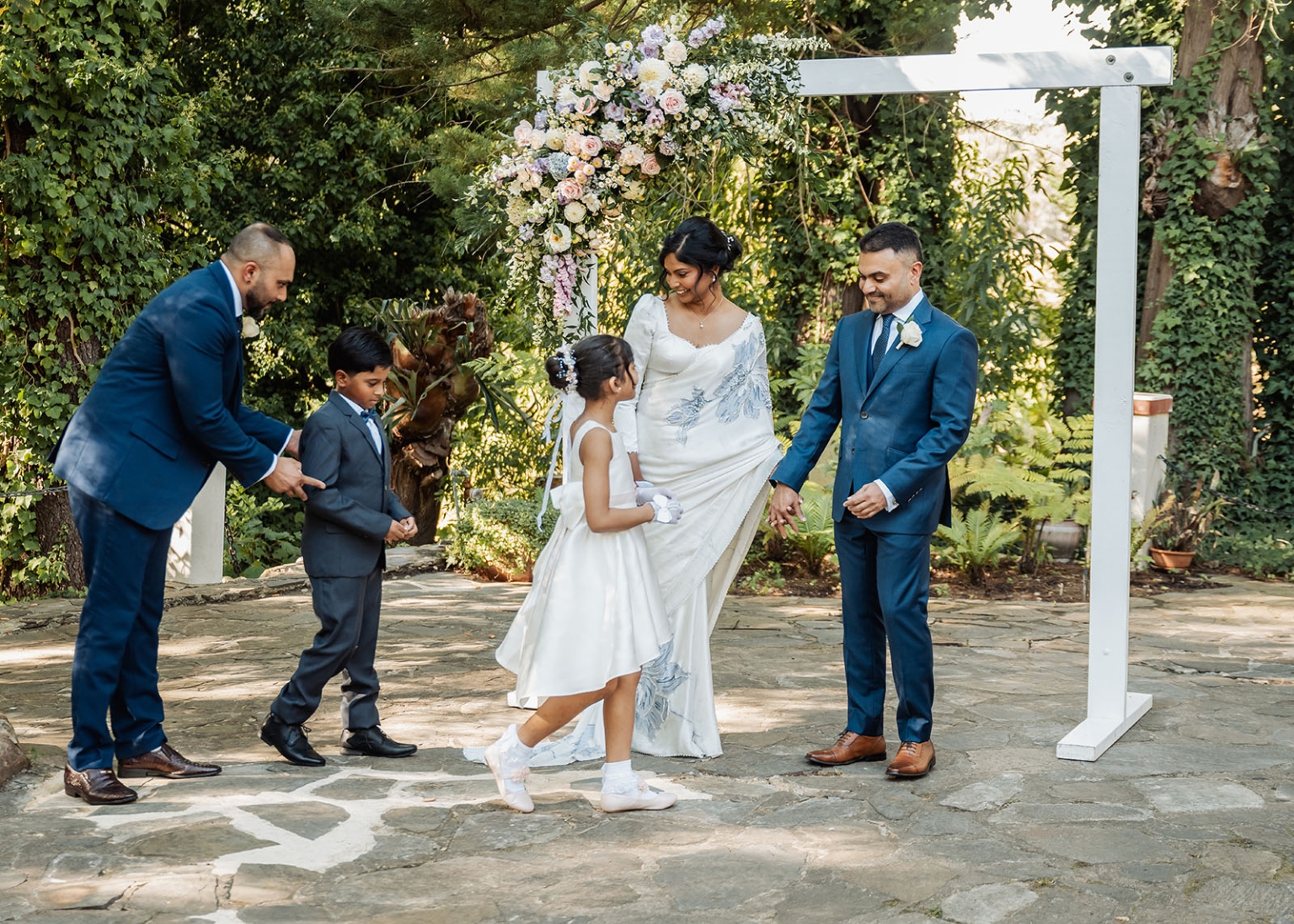 manor wedding in basket range - methmini & aravinda 139 Bride and groom under floral arch with family, outdoor wedding celebration.