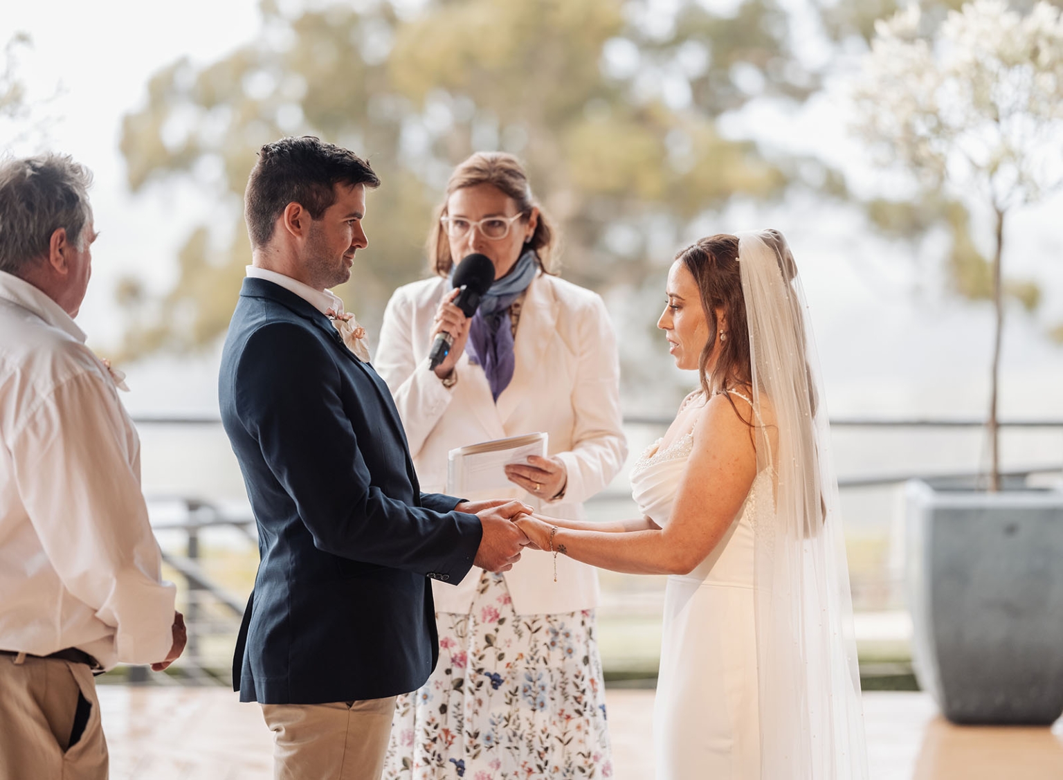 the lane vineyard wedding - caitlyn & craig 120 Outdoor wedding ceremony with bride in lace gown, groom in blue suit, under serene nature setting.