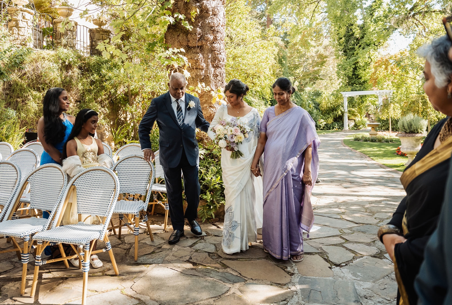 manor wedding in basket range - methmini & aravinda 133 Bride in white saree with parents at serene outdoor wedding ceremony.