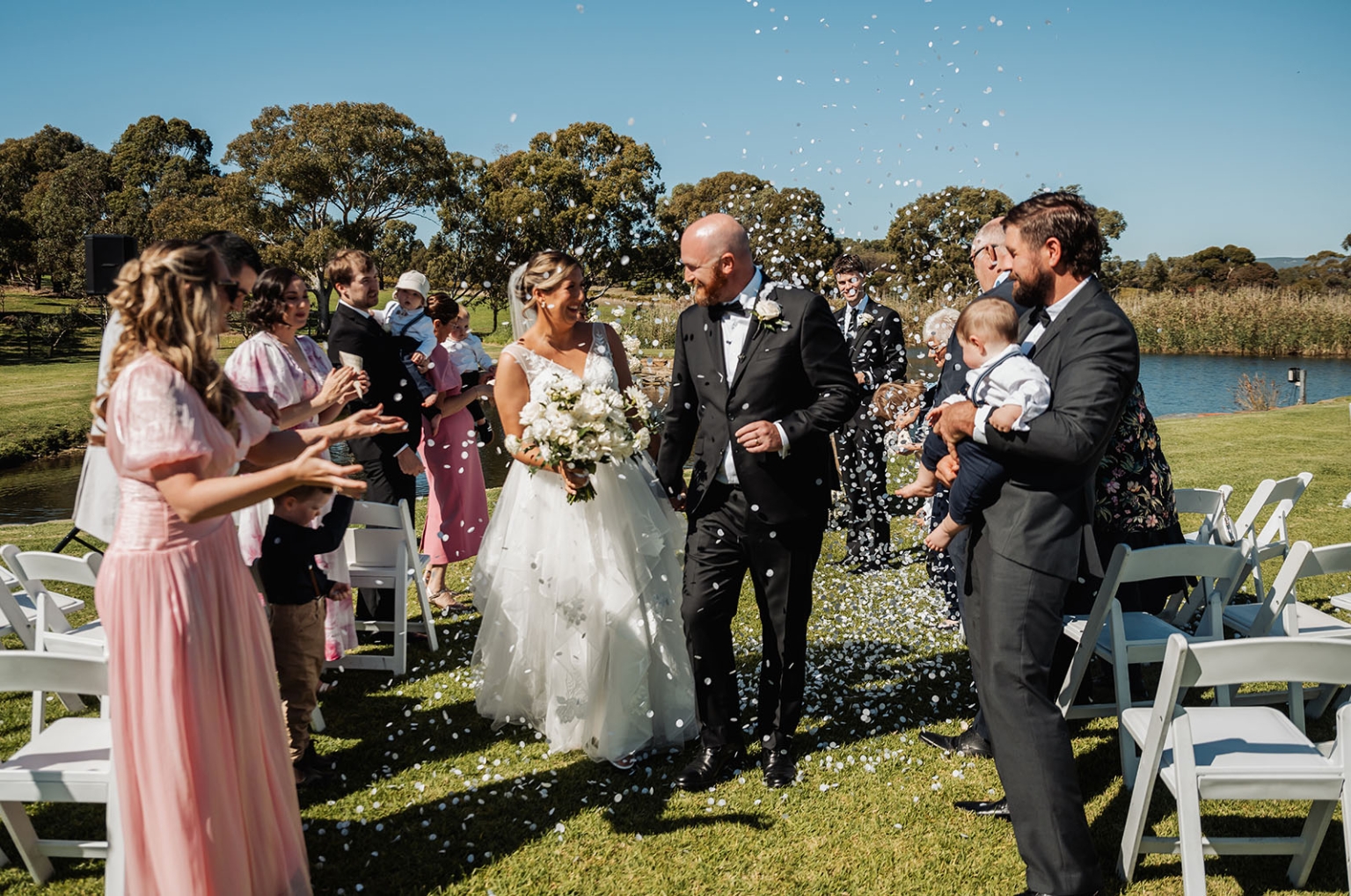 lloyd brothers wedding - dajana & tom 19 Bride and groom walk joyfully down aisle at outdoor wedding ceremony.
