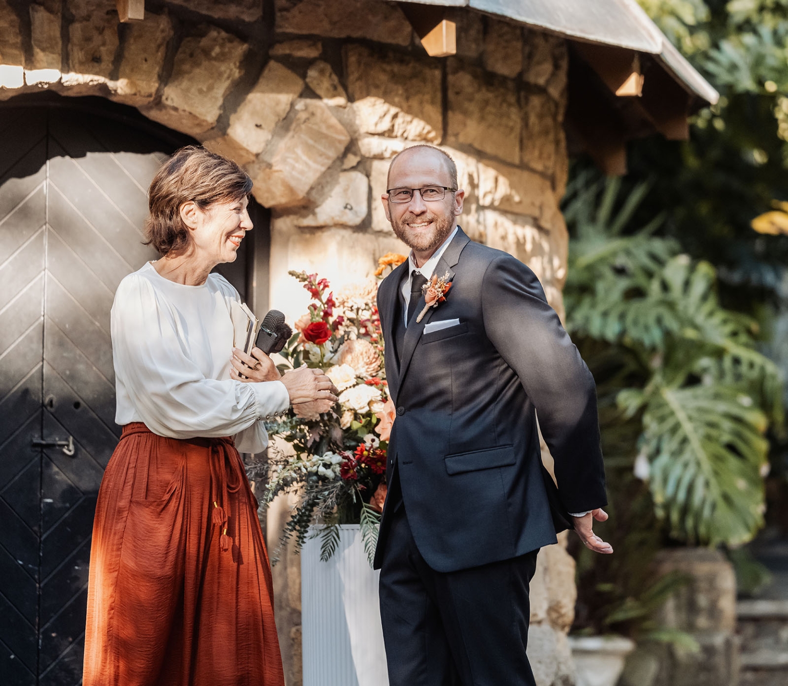adelaide hills wedding at the manor - jo & dan 16 Outdoor wedding ceremony with groom, officiant, and floral arrangements at rustic stone venue.