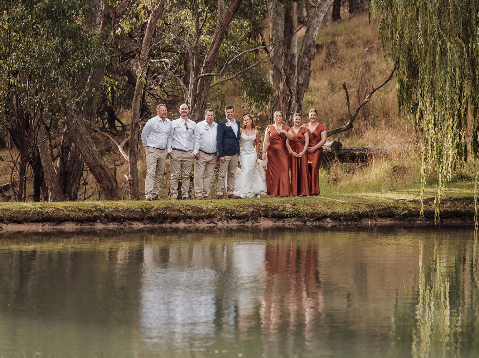 the lane vineyard wedding - caitlyn & craig 107 Wedding party by a serene lakeside, elegant attire, lush natural scenery.
