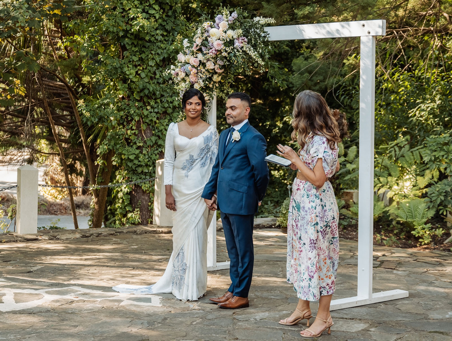 manor wedding in basket range - methmini & aravinda 138 Outdoor wedding ceremony with couple under floral arch in lush greenery.