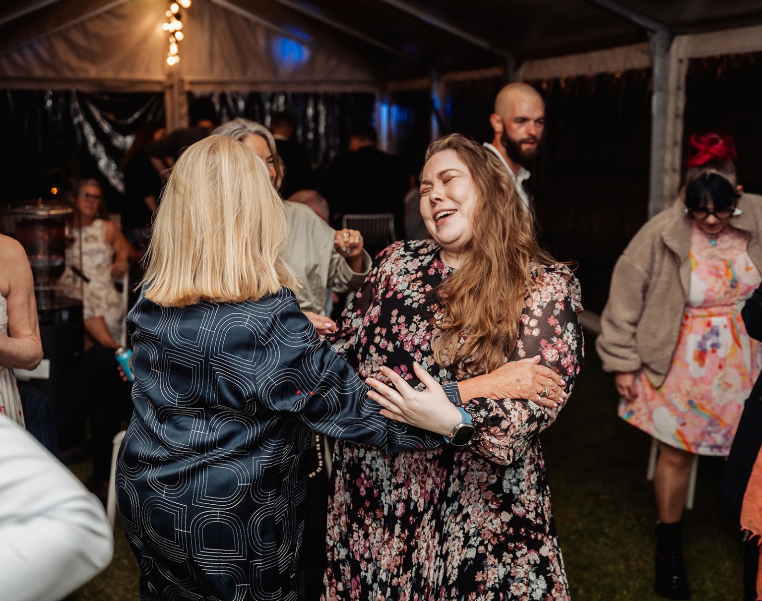 comida wedding - georgia & james 54 Dancing at a vibrant tent party with friends enjoying music and festive atmosphere.