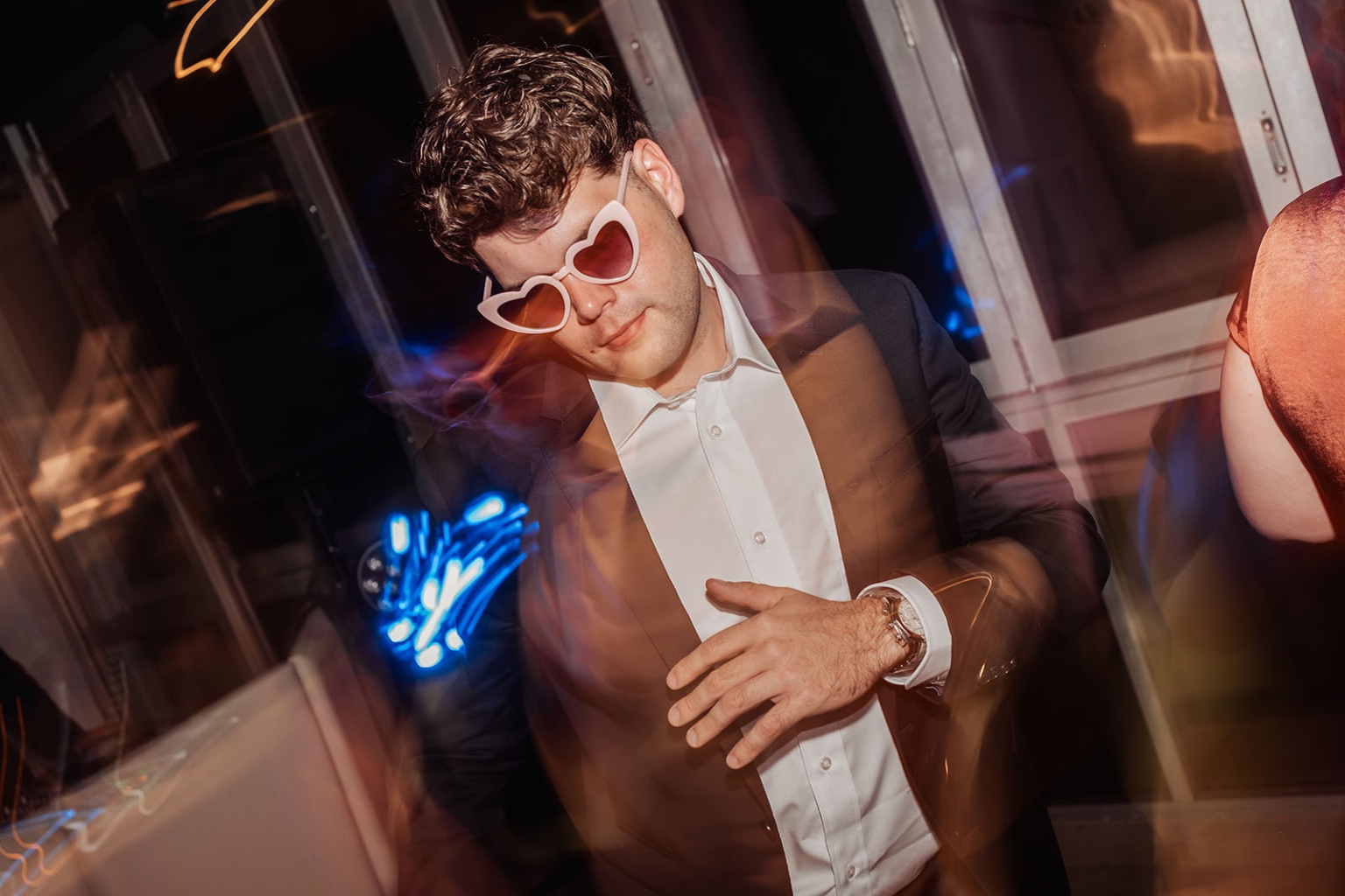 the lane vineyard wedding - caitlyn & craig 140 Person in suit with heart sunglasses dancing at a vibrant party.
