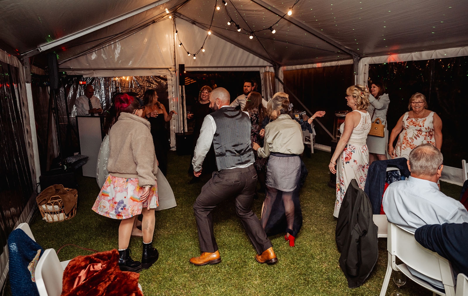 comida wedding - georgia & james 55 Festive gathering under tent with lights, DJ, and dancing on grass floor.