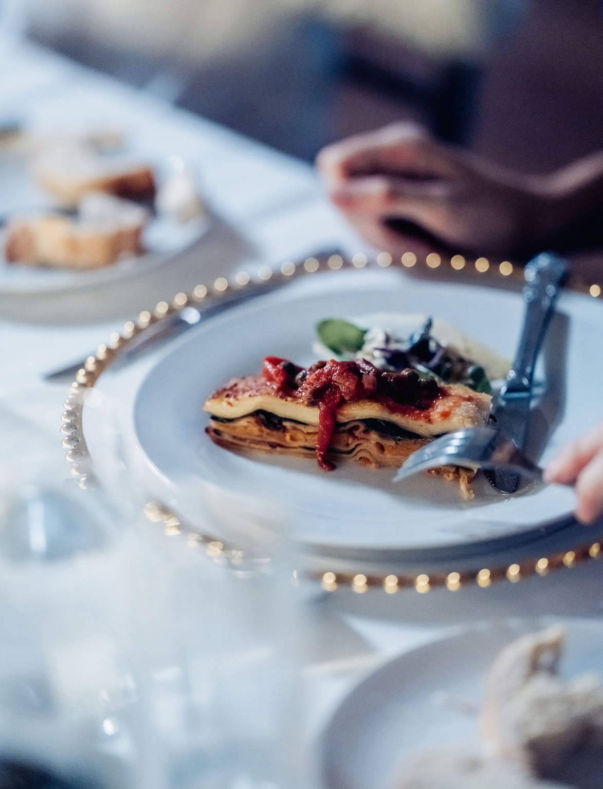 adelaide's st peter's cathedral wedding - irish & nick 56 Plated lasagna with tomato sauce at an elegant restaurant dinner.