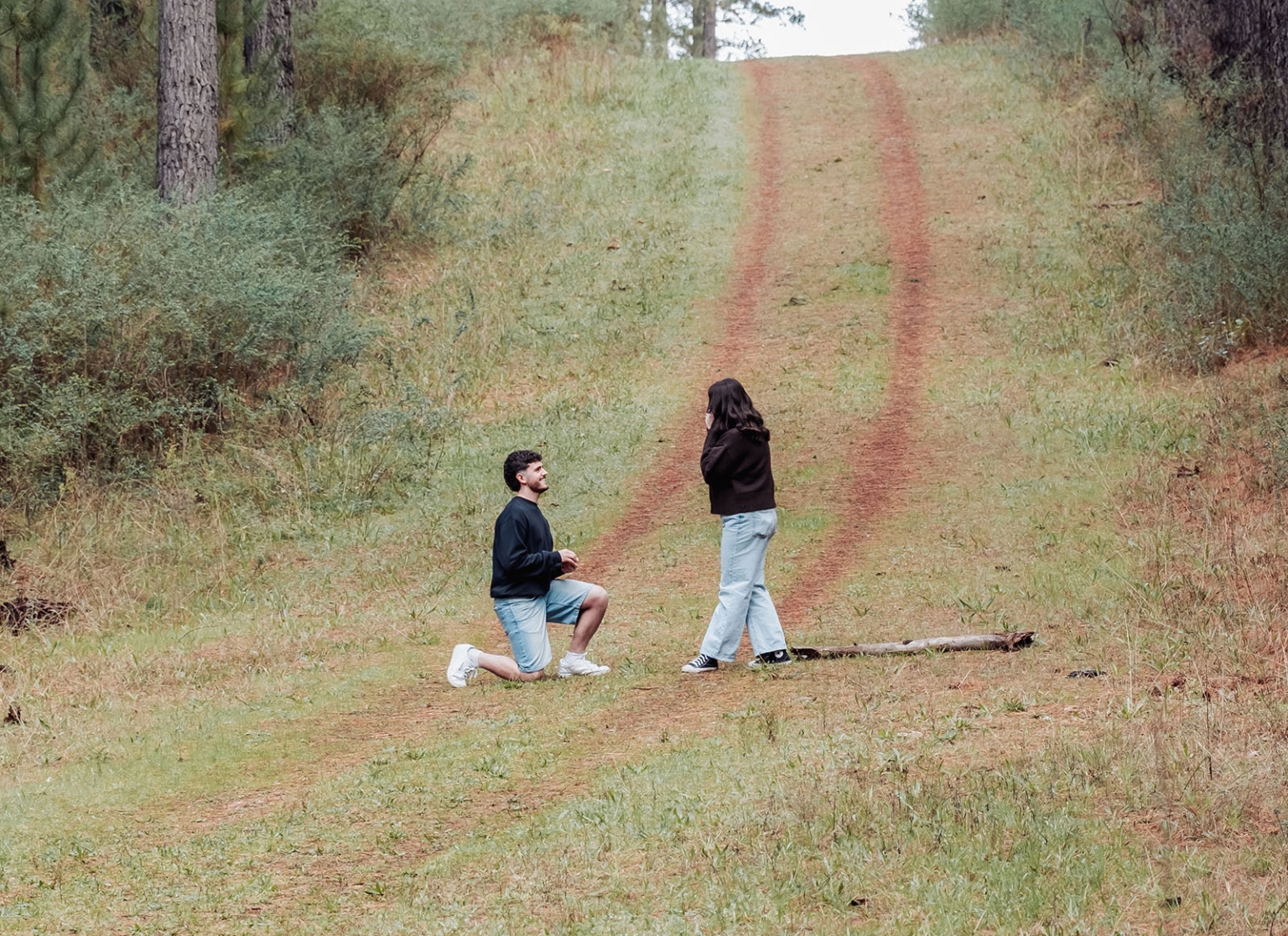 cabn at kuitpo forest proposal - tamsyn & blake 8 Man proposes on grassy hill; emotional moment against serene, natural backdrop.
