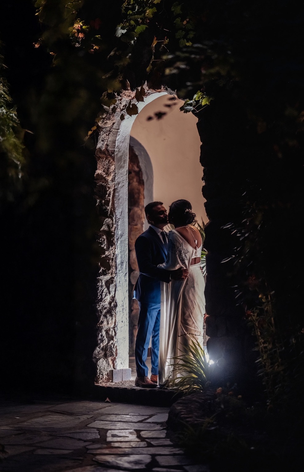 manor wedding in basket range - methmini & aravinda 162 Couple embraces in a rustic, illuminated archway; wedding or engagement scene with timeless elegance.