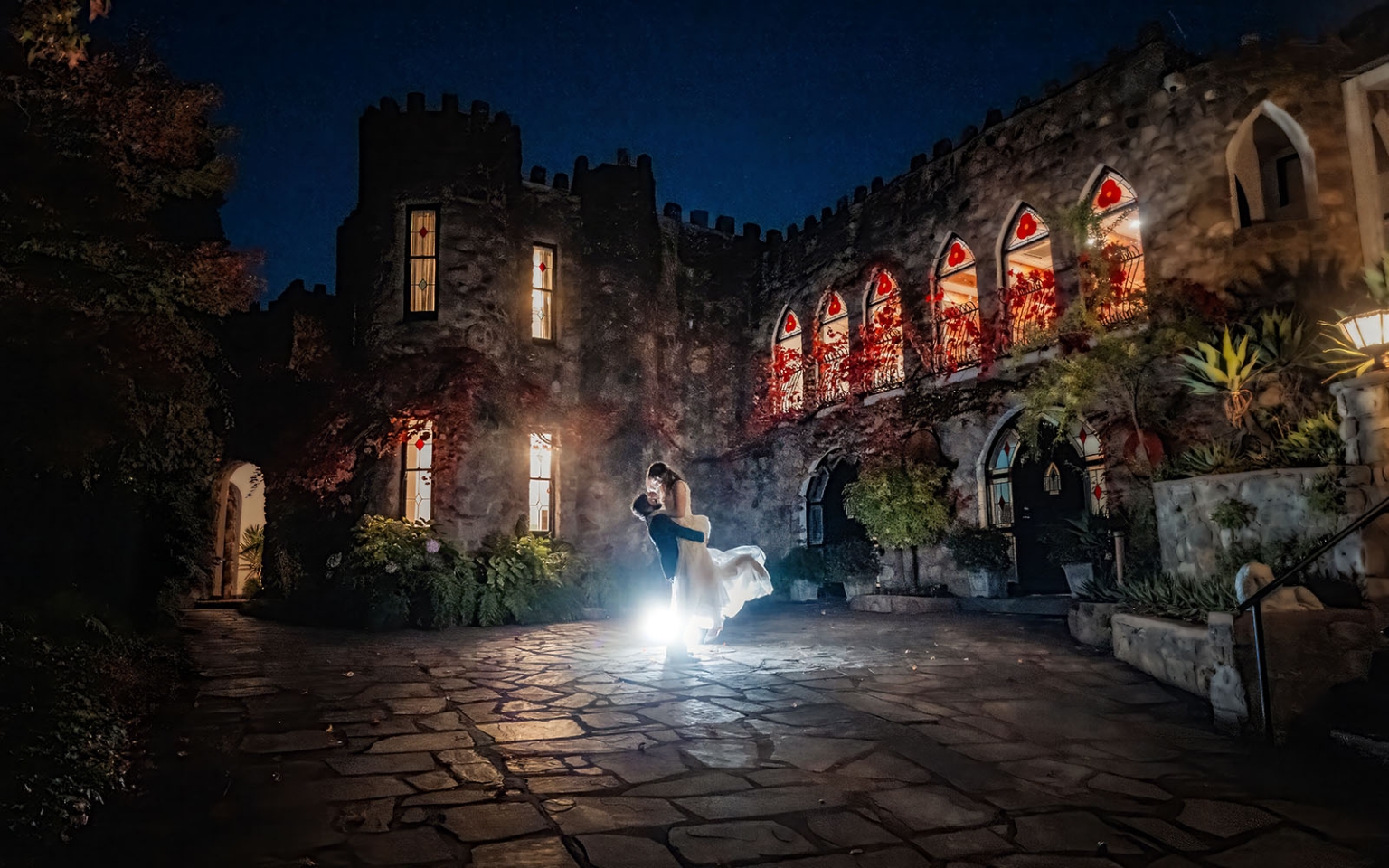 beautiful manor basket range wedding - sophie & theodore 138 Romantic couple dancing at night in front of illuminated castle with stained glass windows.