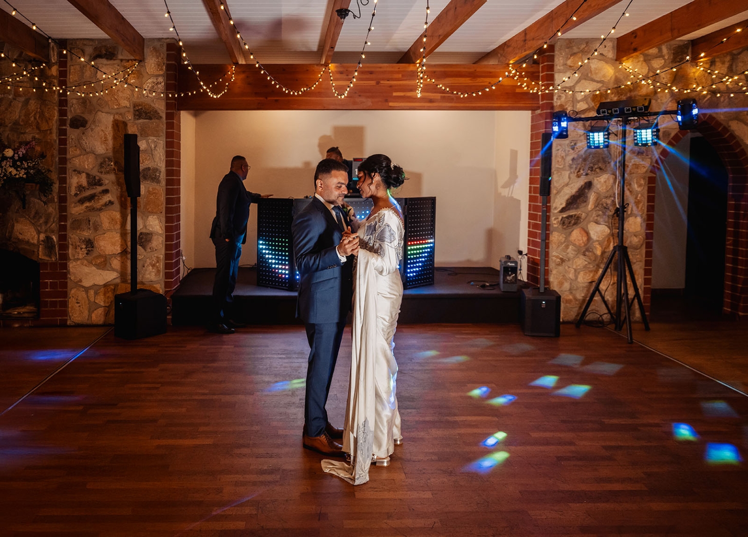 manor wedding in basket range - methmini & aravinda 169 Elegant couple dancing at wedding reception with romantic lighting and DJ in background.