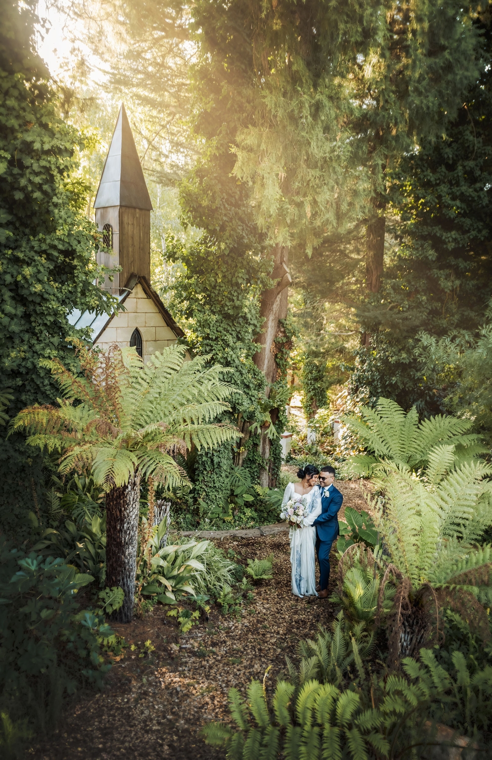 manor wedding in basket range - methmini & aravinda 144 Couple embracing in a lush garden by an ivy-covered chapel.