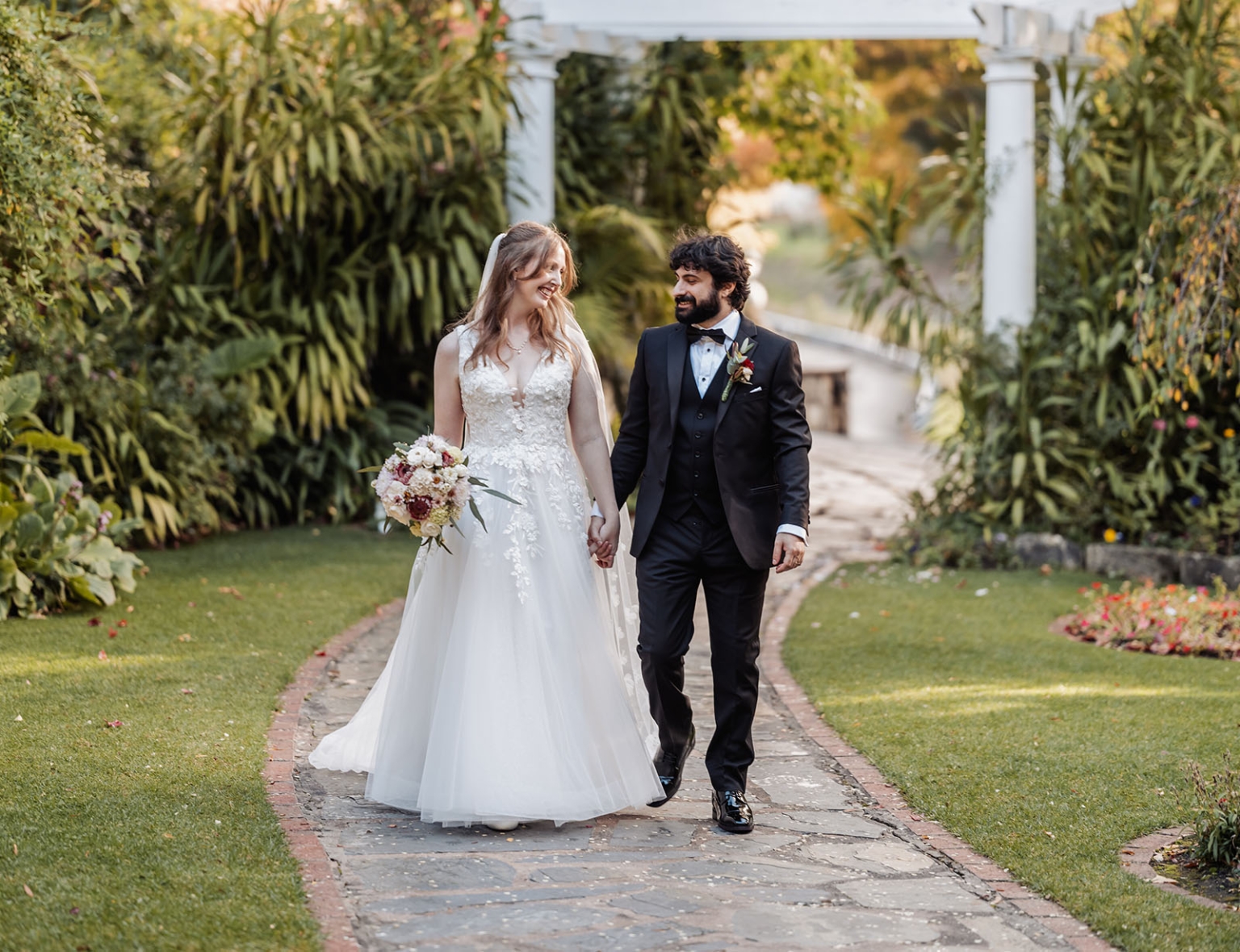 beautiful manor basket range wedding - sophie & theodore 113 Romantic garden wedding with bride and groom in elegant attire under a white arbor.