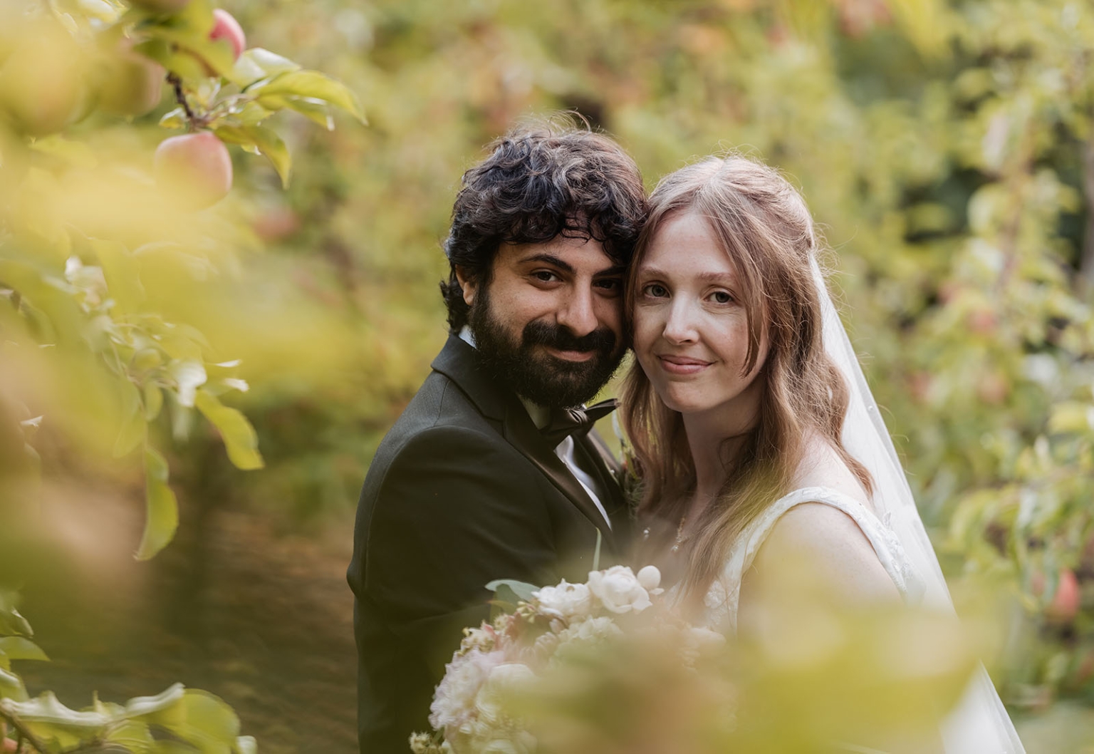 beautiful manor basket range wedding - sophie & theodore 128 Couple in apple orchard, wedding attire, romantic embrace, soft focus, natural light.