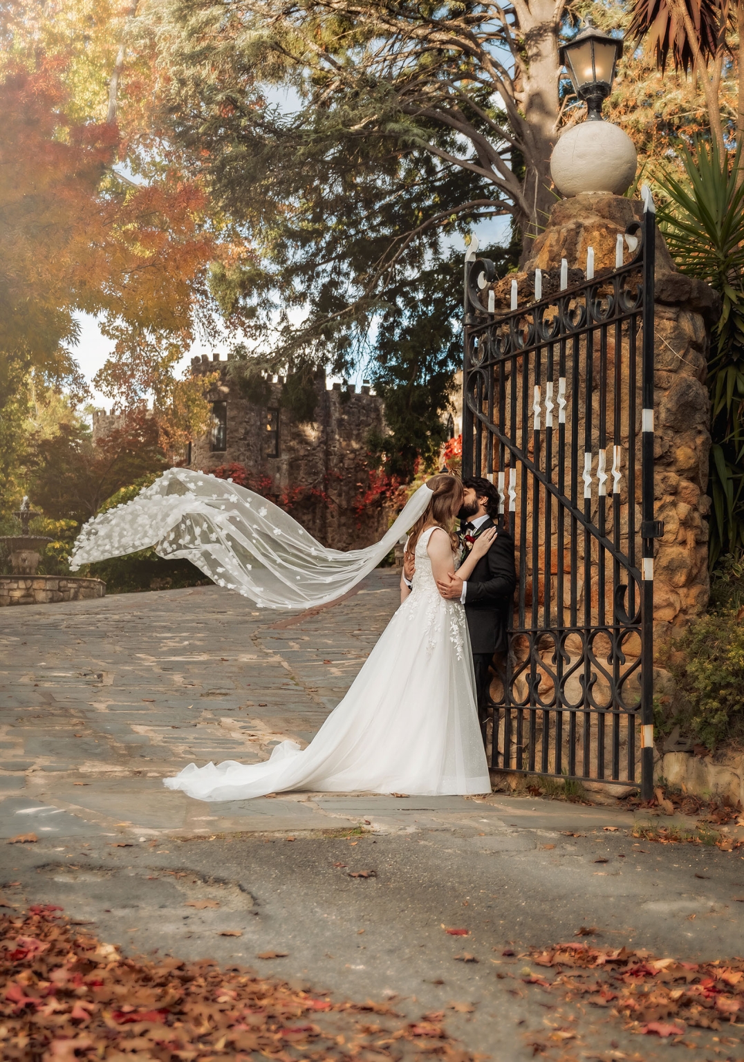 beautiful manor basket range wedding - sophie & theodore 125 Bride and groom embrace in scenic autumn setting with colorful foliage and historic architecture.