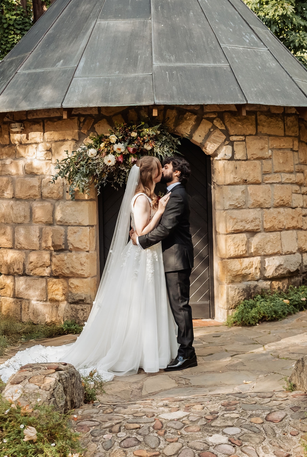 beautiful manor basket range wedding - sophie & theodore 107 Newlywed couple kissing in a picturesque, rustic garden setting.