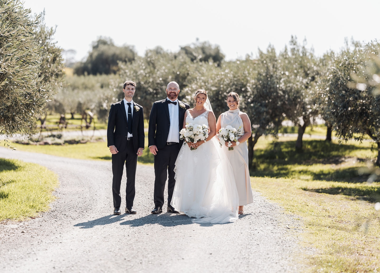 lloyd brothers wedding - dajana & tom 32 Outdoor wedding celebration in olive grove: bride, groom, attendants, formal attire, joyful moment.