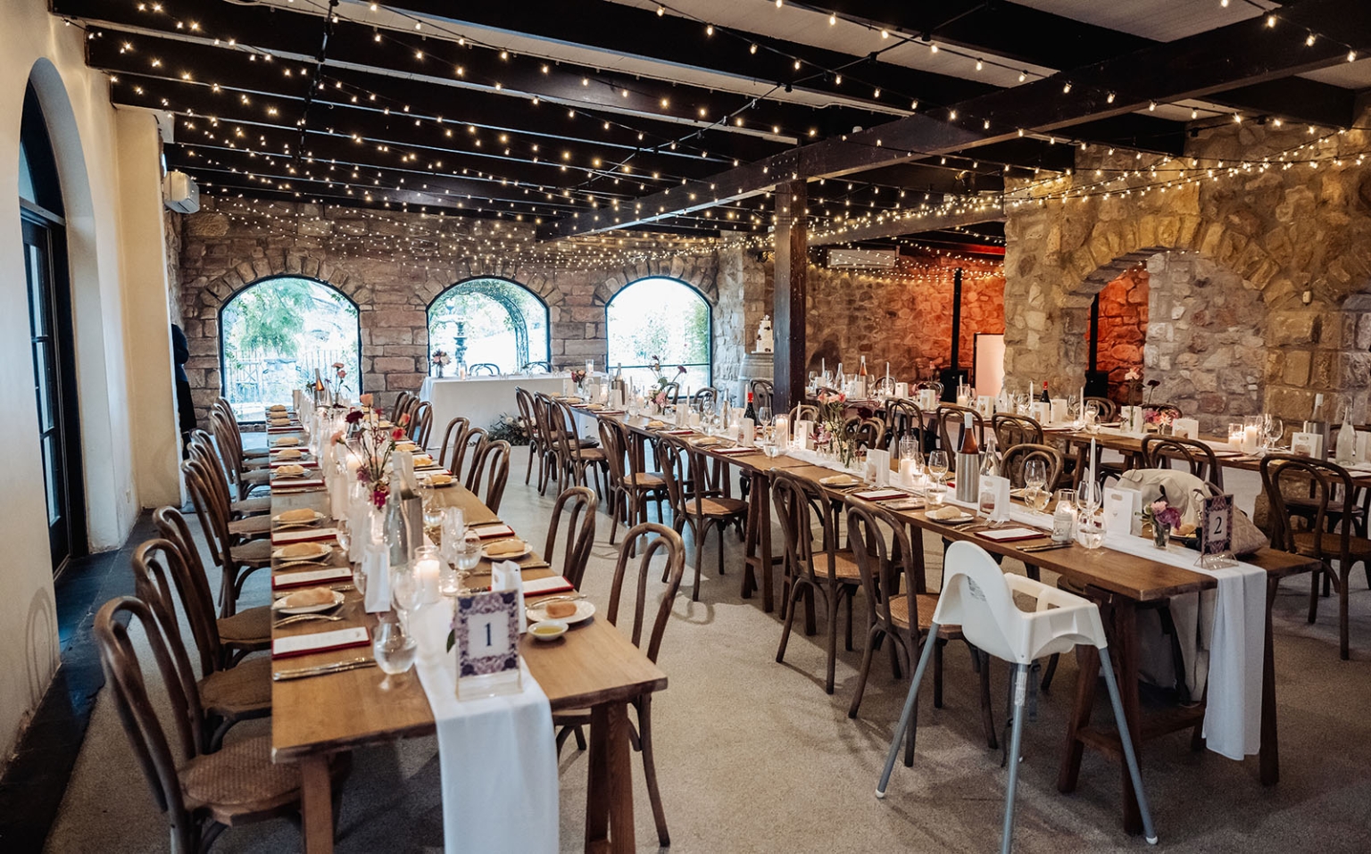beautiful manor basket range wedding - sophie & theodore 130 Rustic indoor wedding reception with wooden tables, fairy lights, and charming brick walls.