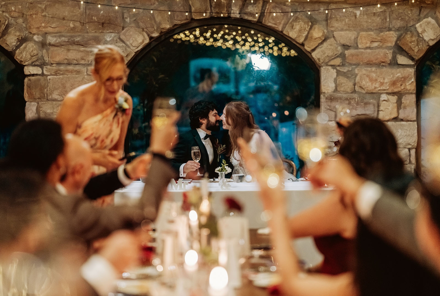 beautiful manor basket range wedding - sophie & theodore 141 Bride and groom kiss during rustic wedding reception toast at candlelit head table.