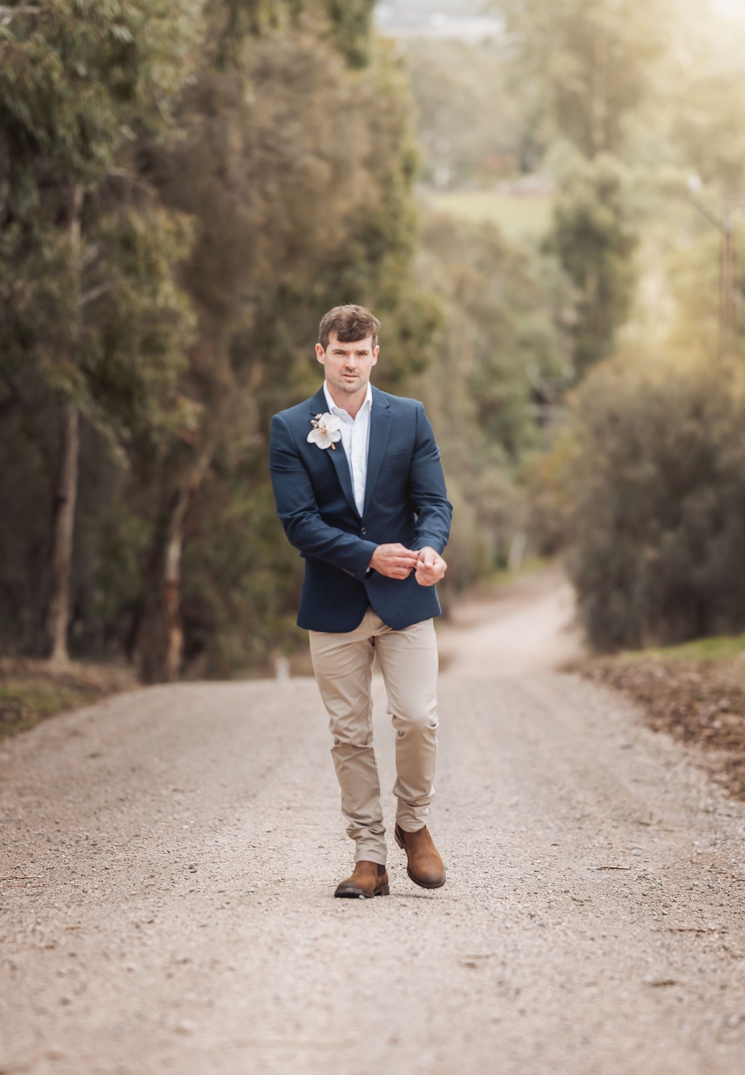 the lane vineyard wedding - caitlyn & craig 74 Man in formal attire walking on scenic dirt road during golden hour.