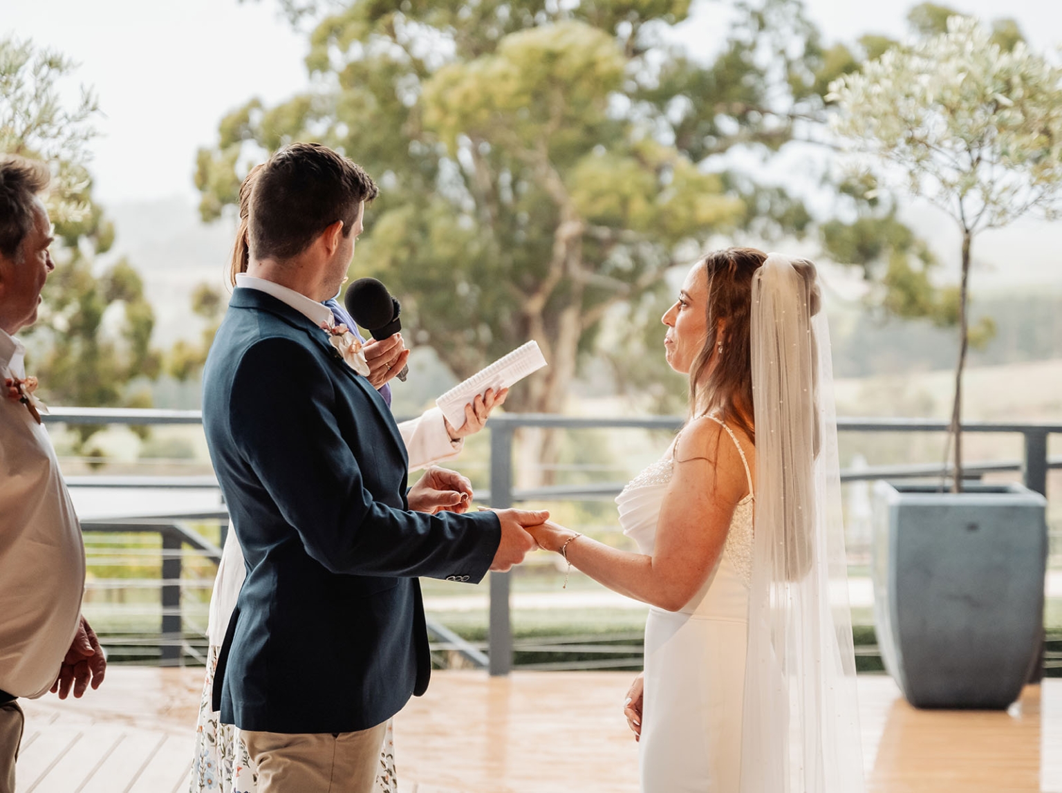 the lane vineyard wedding - caitlyn & craig 122 Outdoor wedding ceremony with bride, groom, officiant, lush greenery, elegant attire, serene backdrop.