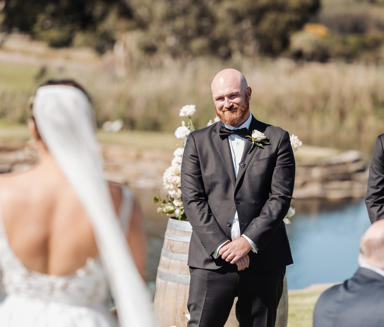 lloyd brothers wedding - dajana & tom 10 Bride and groom in picturesque outdoor wedding by water with floral arrangements.
