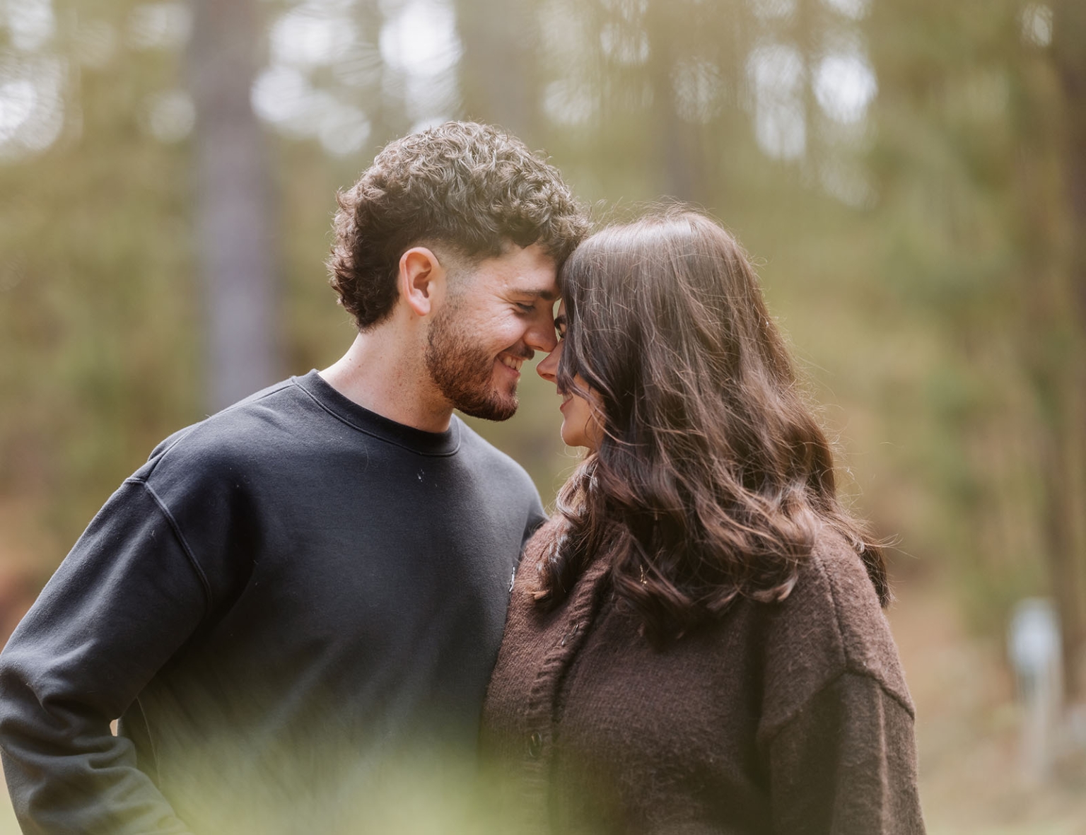 cabn at kuitpo forest proposal - tamsyn & blake 18 Couple shares intimate moment in serene forest setting, foreheads touching, natural light illuminating.