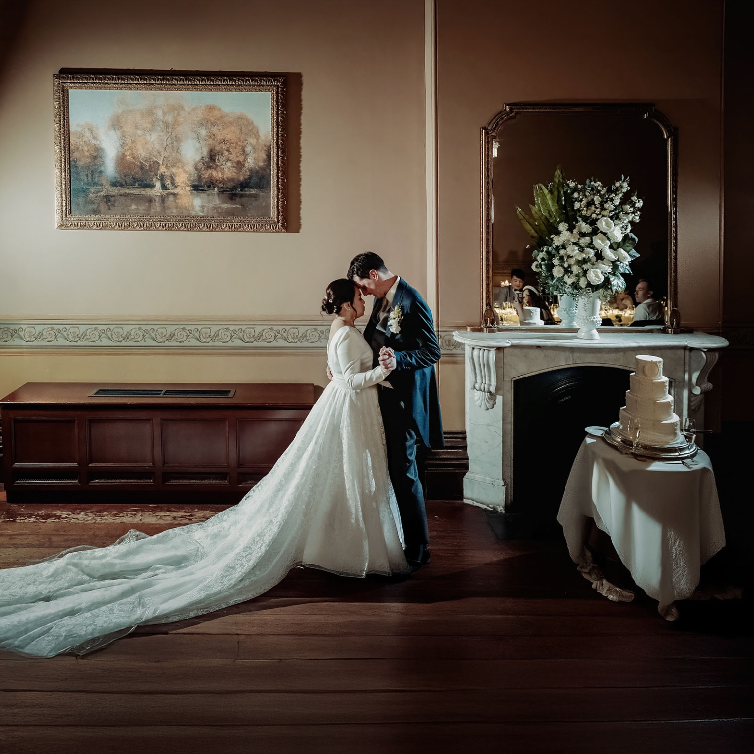 adelaide's st peter's cathedral wedding - irish & nick 61 Vintage wedding couple sharing romantic moment beside cake and fireplace in elegant reception room.