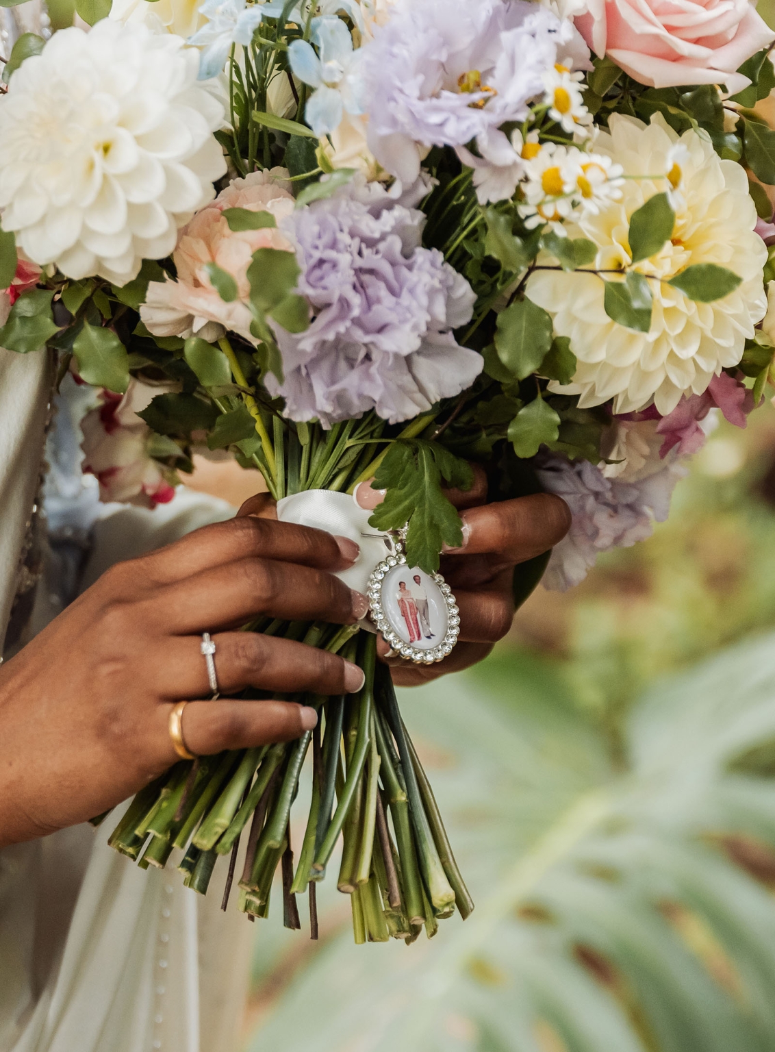 manor wedding in basket range - methmini & aravinda 129 Bride holding elegant bouquet with dahlias, roses, charm, and rings in a garden setting.