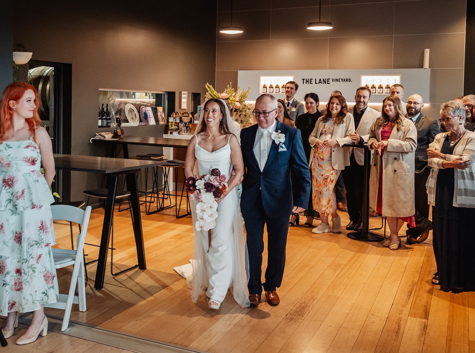 the lane vineyard wedding - caitlyn & craig 118 Bride and father walk down aisle at vineyard wedding reception, surrounded by smiling guests.
