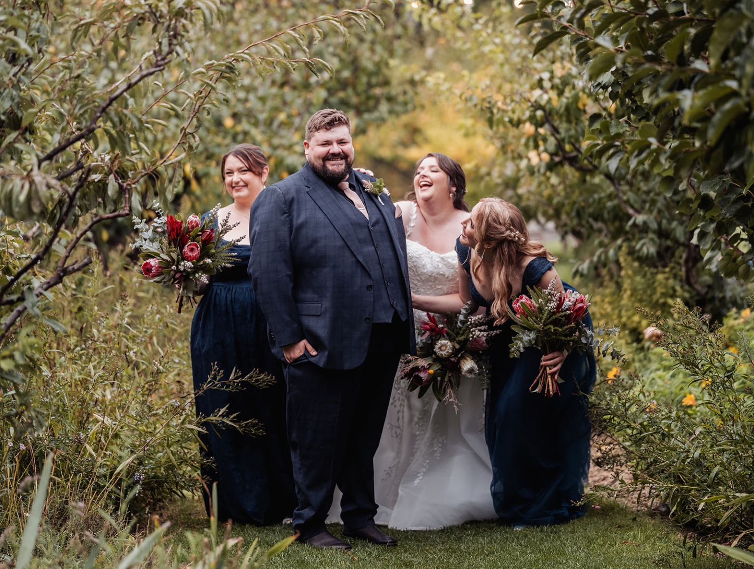 comida wedding - georgia & james 32 Outdoor wedding scene with bride, groom, bridesmaids, lush greenery, vibrant bouquets, joyful smiles.
