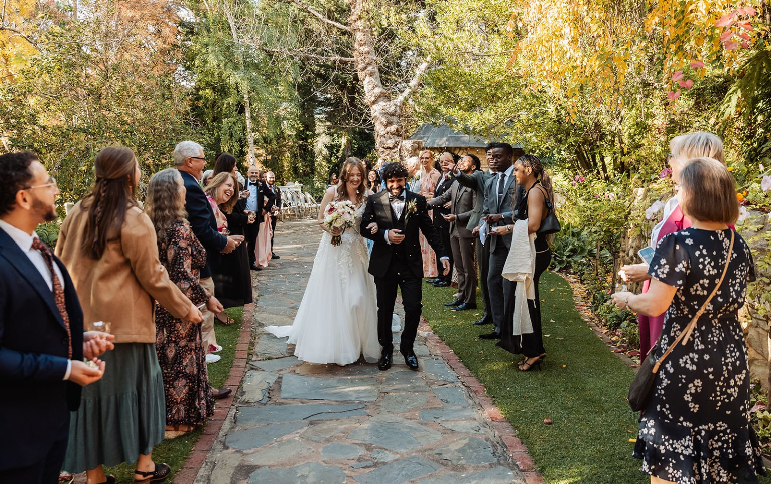 beautiful manor basket range wedding - sophie & theodore 108 Bride and groom exit garden wedding with joyful guests and beautiful floral surroundings.